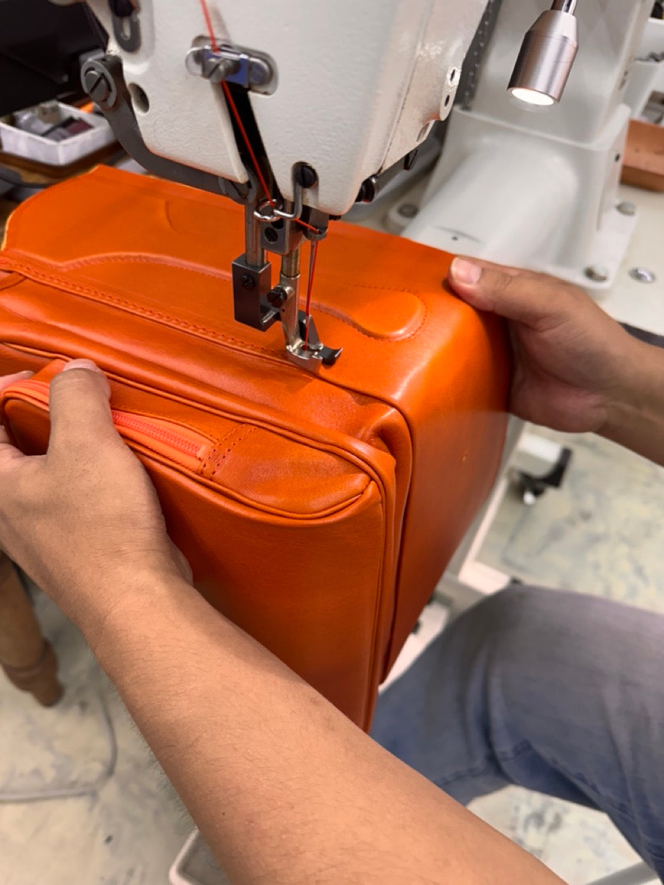 お父さんが立体に組み立てたランドセルをミシンで縫製している