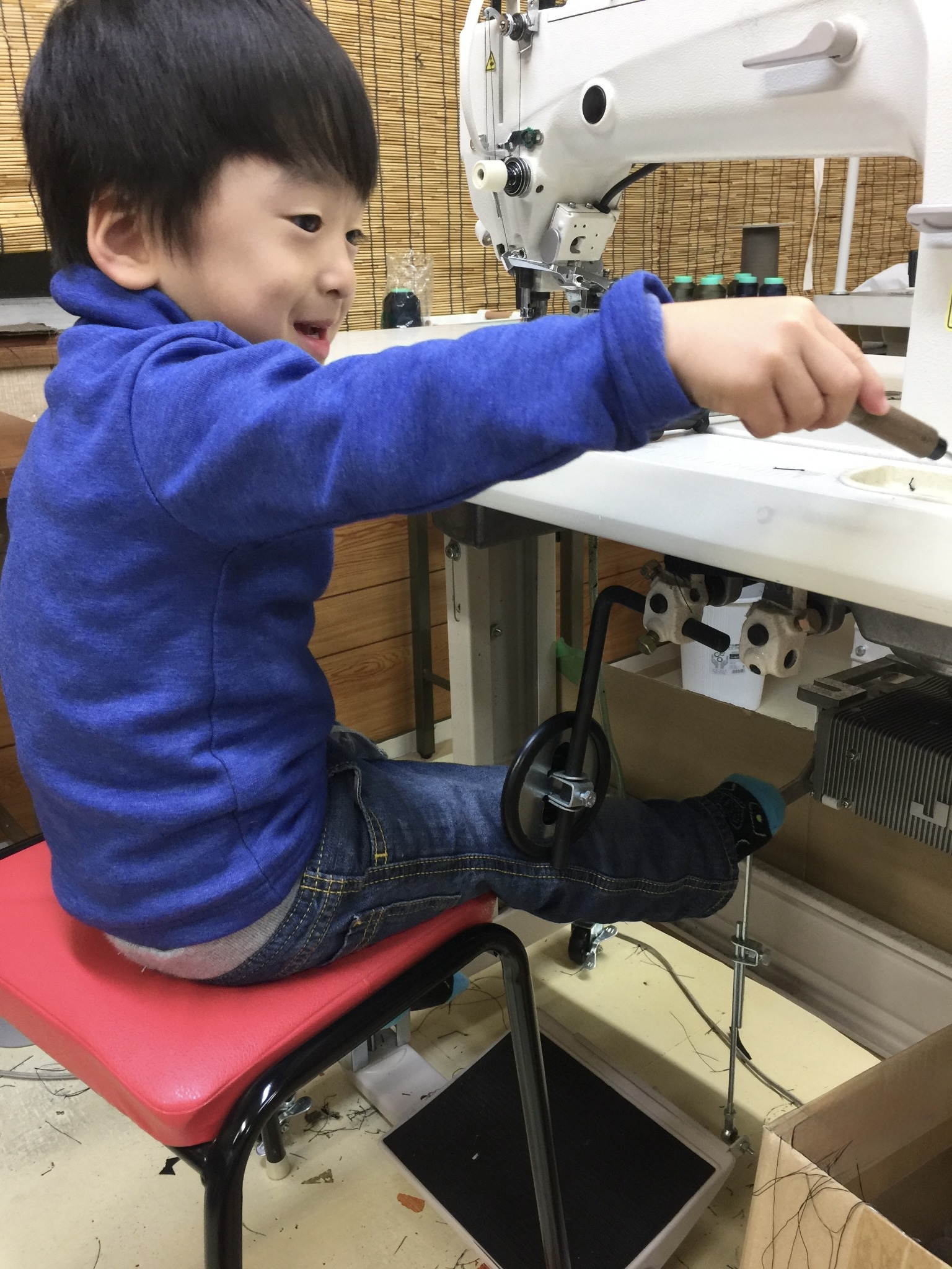 小さな子どもが工業用ミシンを使って革を縫っている様子