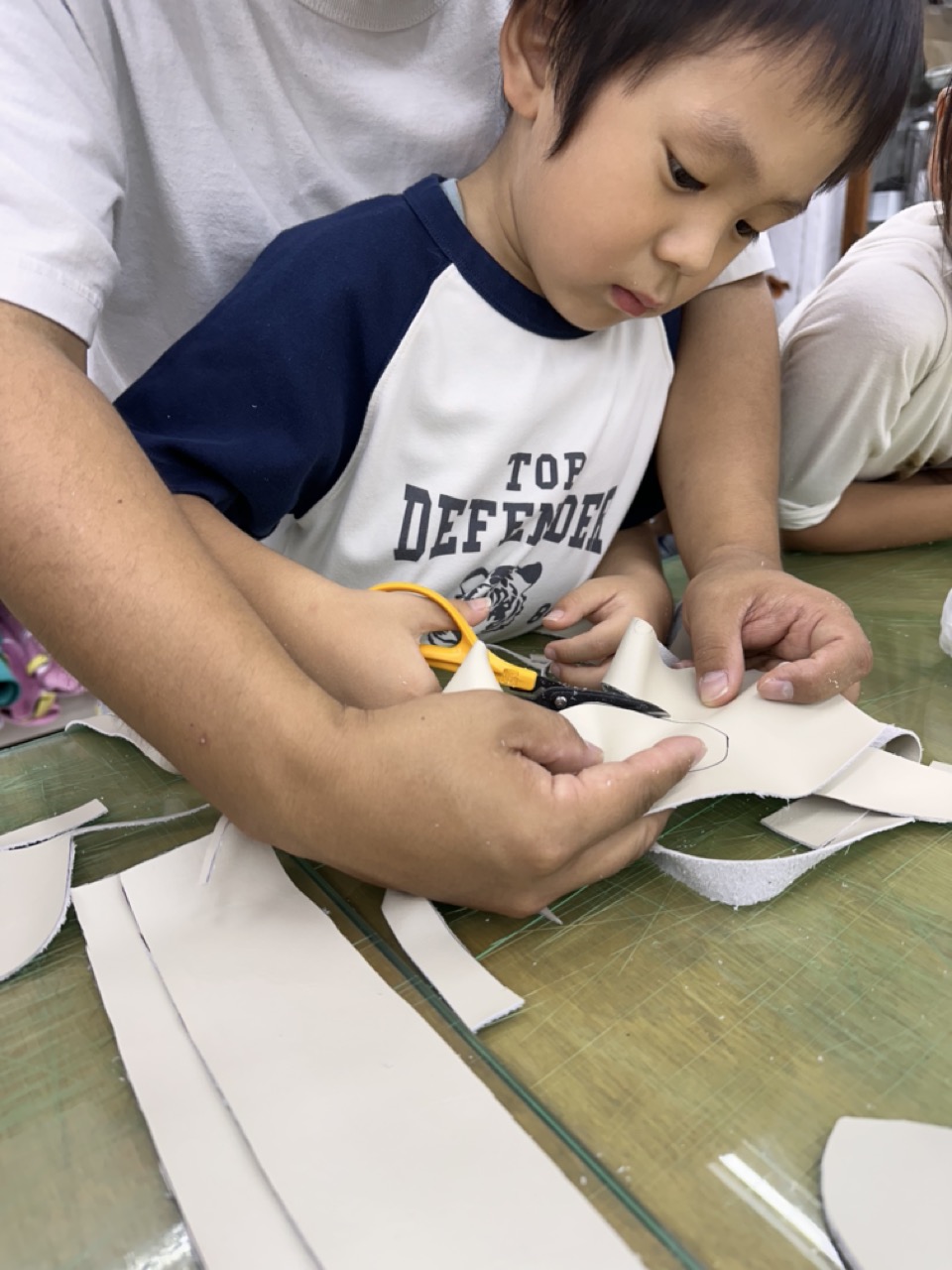 子どもがハサミで革を裁断する様子