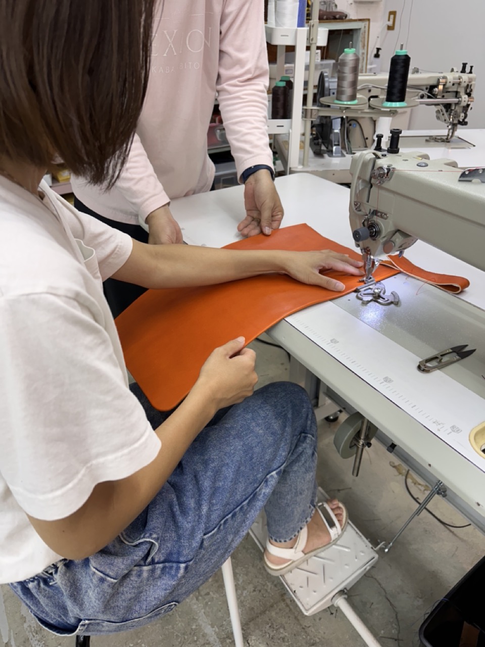 大人が工業用ミシンで革を縫う様子